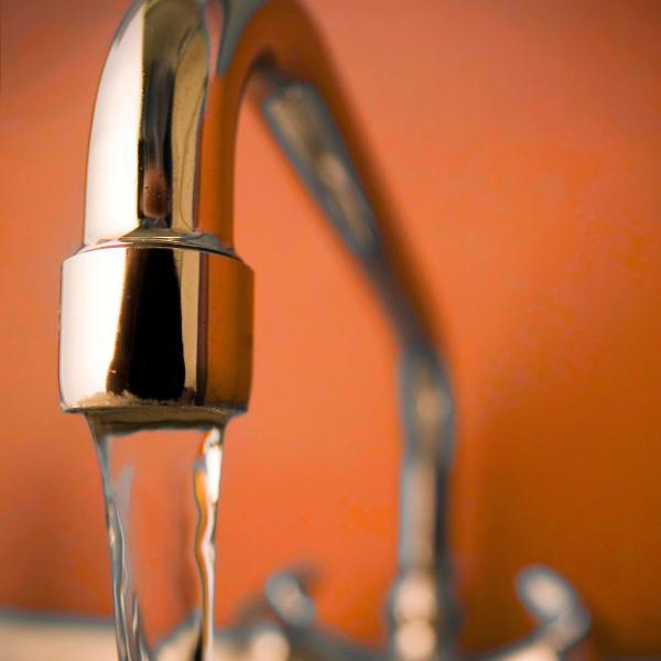 robinet avec de l'eau qui coule sur fond orange